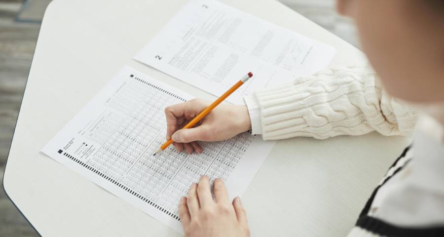 Student carefully marking answers on a standardised test paper — the focused preparation required for TOEFL or IELTS for Ivy League applications