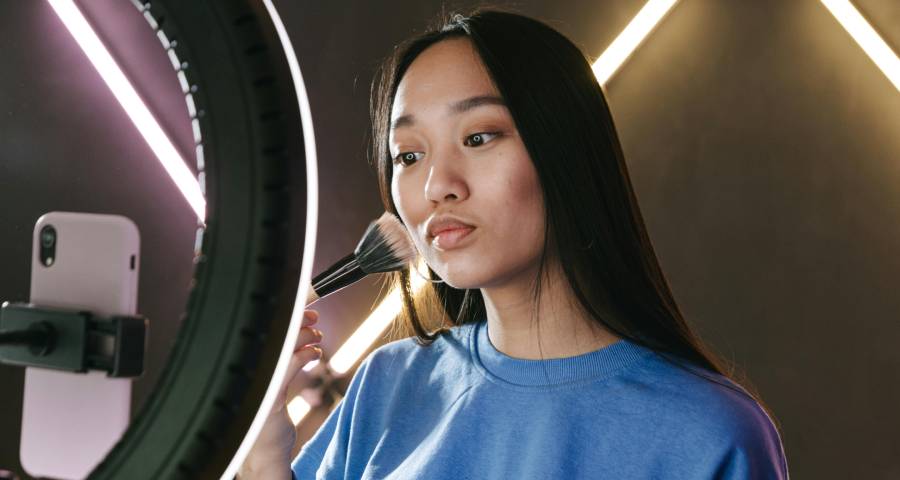 Young woman recording content on smartphone with ring light building her personal online presence