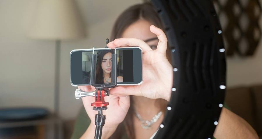 Student vlogger setting up smartphone and ring light to create educational content for YouTube channel 
