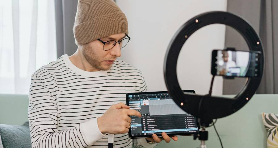 Young man creating video content with smartphone and ring light documenting his interests and projects