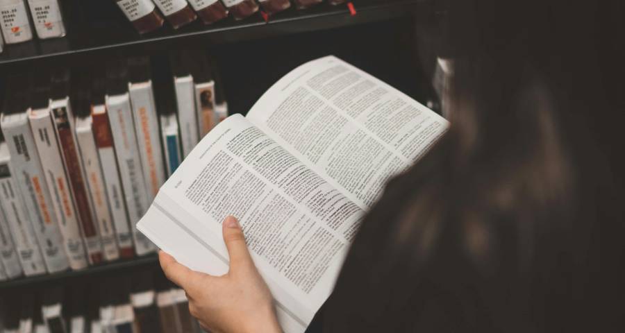 Smiling young Indian student reading confidently in a library — representing Gujarati medium students who can reach Ivy League universities