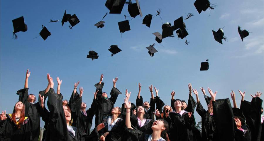 Graduates celebrating success by throwing caps in the air on graduation day