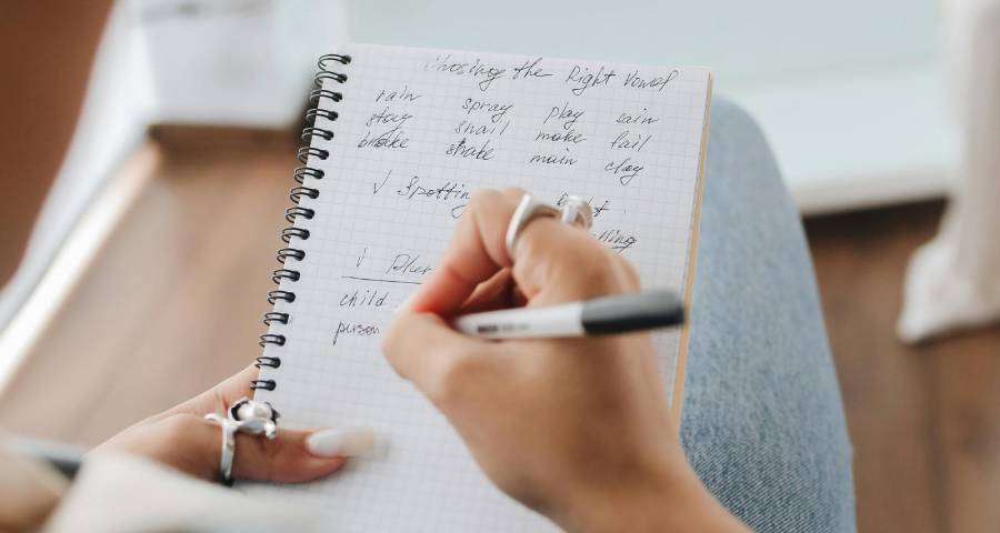 Student writing notes by hand in notebook to create an authentic personal essay for Ivy League application