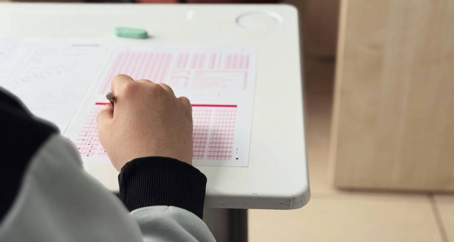 Student focused and writing during a high-stakes exam — the intense academic pressure that contributes to college application anxiety among Indian students
