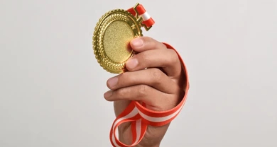 Teenage athlete smiling and holding a gold medal — the competitive sporting achievement that strengthens an Indian student’s Ivy League application profile